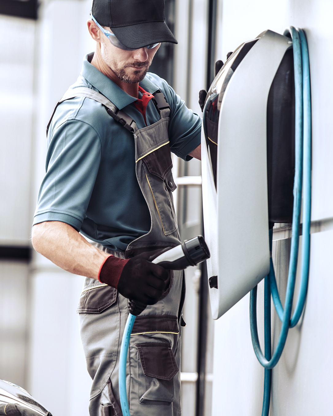 Electrician installing a powerful electric wall charger for EV vehicles at a charging station.