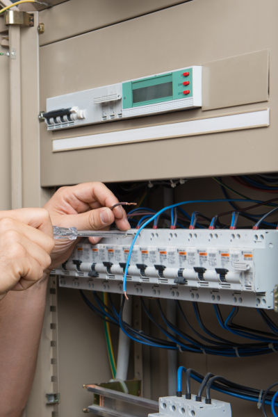 Hands of an electrician fixing a circuit breaker