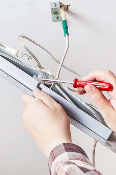 Electrician repairing outdated wiring with a screwdriver.