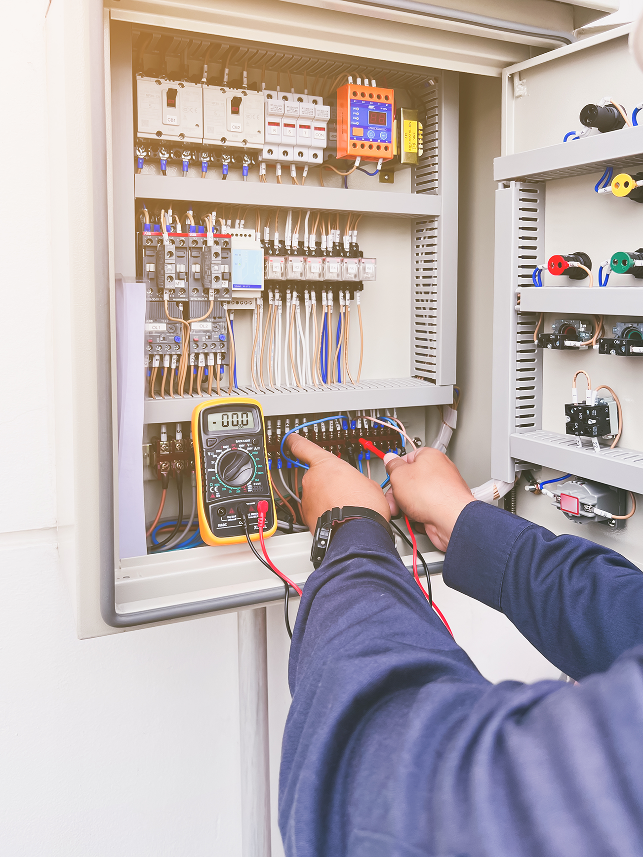 Electrician checking power control panel with a multimeter.