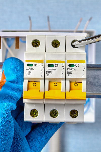 Close-up of a technician repairing and replacing circuit breakers, wearing protective gloves.