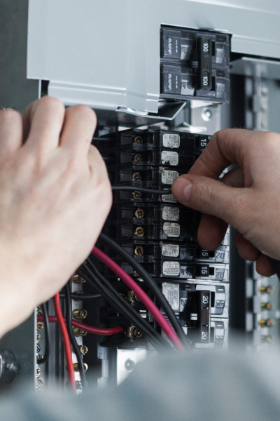 Electrician working on wiring upgrade in an electrical panel.